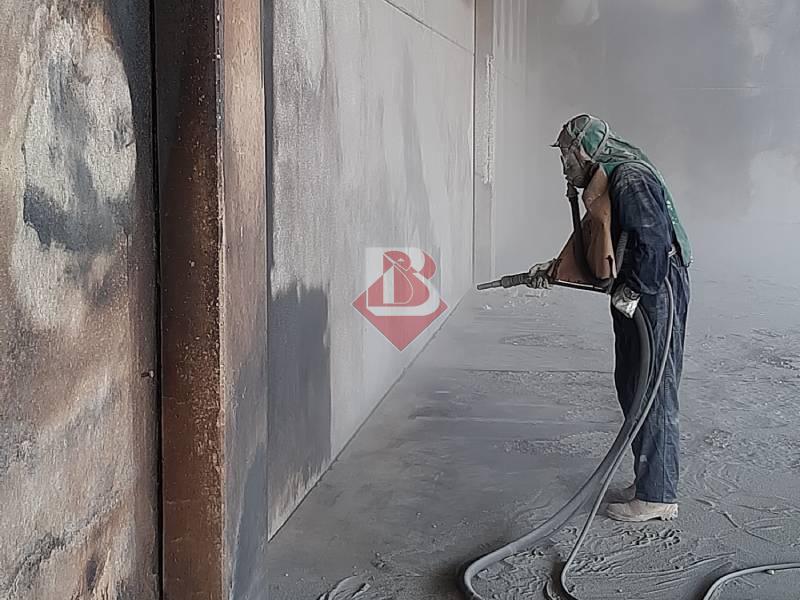 Operaio che esegue la Sabbiatura di una Parete Metallica a Modena: Processo e Vantaggi Operaio che esegue la sabbiatura di una parete metallica in un ambiente industriale a Modena. La sabbiatura è una tecnica di pulizia e preparazione delle superfici utilizzata per rimuovere ruggine, vernici e altri contaminanti, rendendo le superfici pronte per ulteriori lavorazioni. Questa immagine mostra un esempio pratico del processo di sabbiatura in azione, evidenziando l'importanza dell'uso di dispositivi di protezione individuale per garantire la sicurezza dell'operatore.